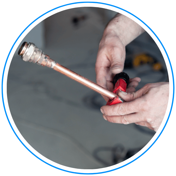 plumber cuts copper pipe with tool